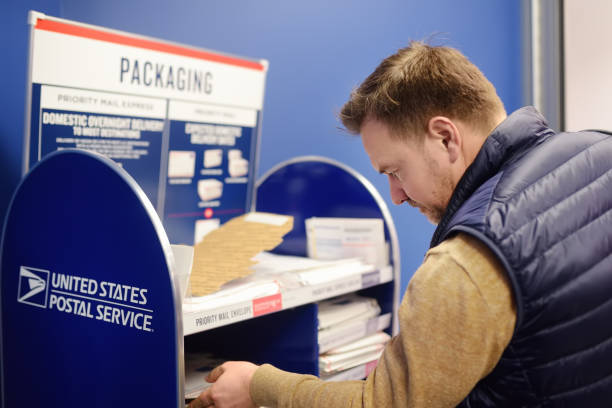 NEW YORK, USA - 23 october 2018: Mature man at the post office chooses an packaging - envelope / box for mailing. stock photo