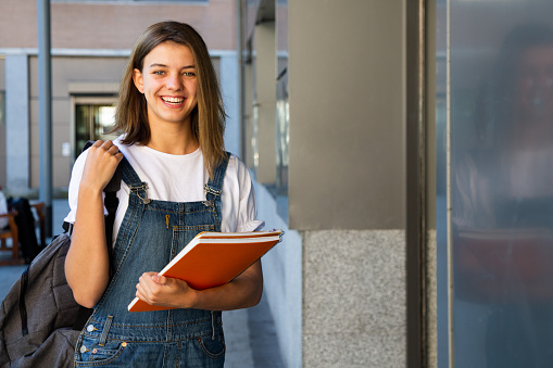 Portrait of a happy teen student girl at the entrance of the school
