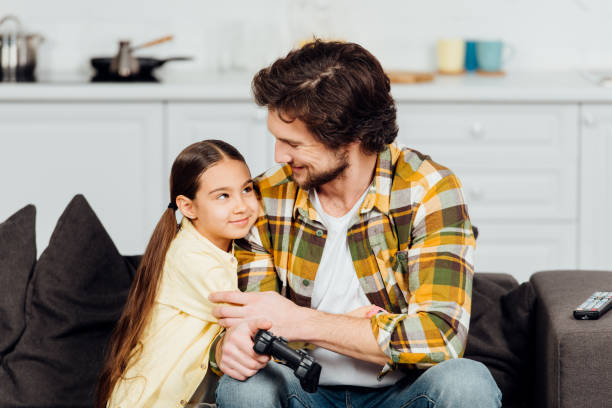 istock happy kid hugging cheerful father holding joystick at home 1154038462
