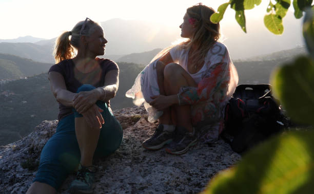 kobiety wędrówki zrelaksować się nad doliną poniżej - hiking young women outdoors t shirt zdjęcia i obrazy z banku zdjęć