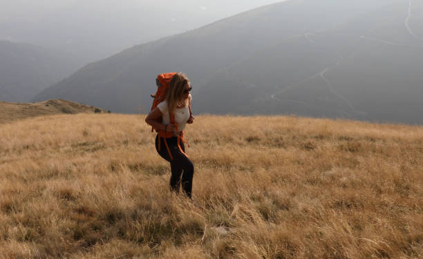 istock Female hiker walks up grassy hillside 1154038846