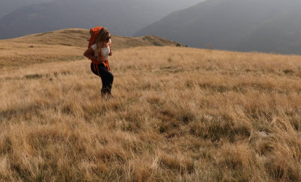 istock Female hiker walks up grassy hillside 1154039029