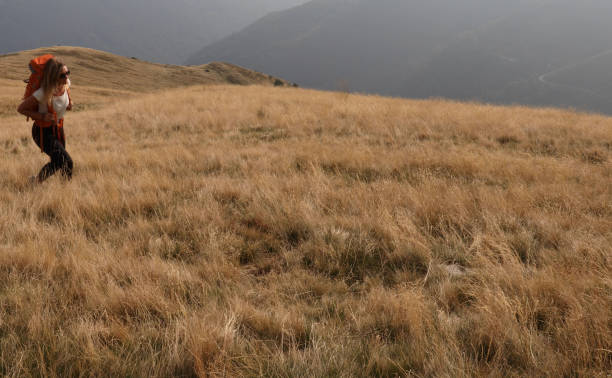 istock Female hiker walks up grassy hillside 1154039061