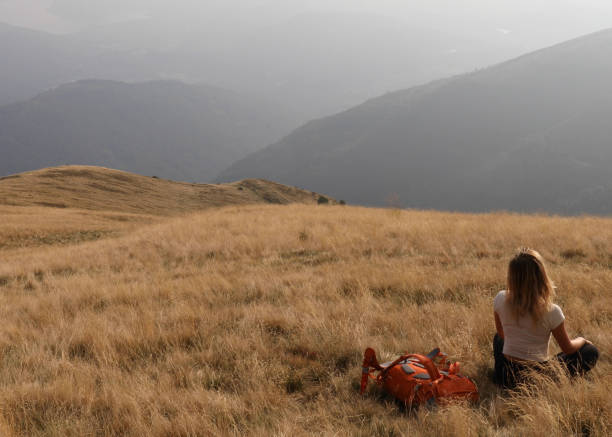 istock Female hiker sits down on grassy hillside 1154039234