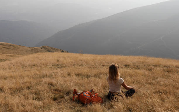 Female hiker sits down on grassy hillside