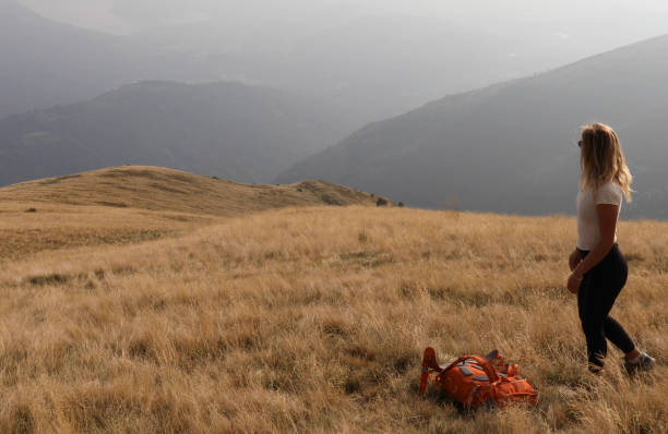 istock Female hiker sets backpack down on grassy hillside 1154039887