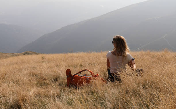 istock Female hiker holding phone sits down on grassy hillside 1154040448