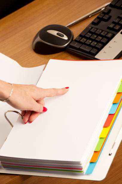 istock Woman hand on a front page of a business folder checking data 1154041299