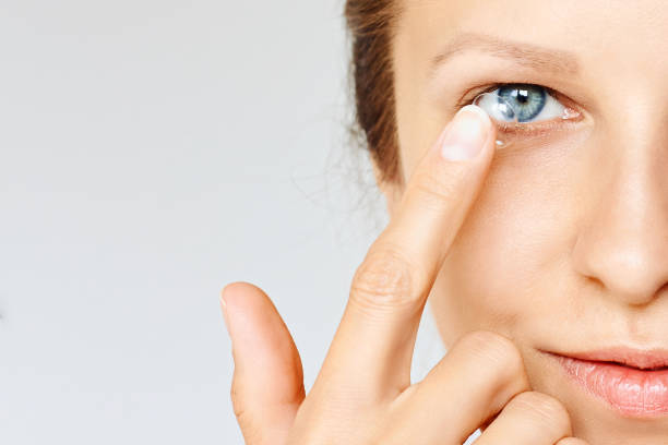 la mujer joven pone lentes de contacto en su ojo. - human eye eyesight optometrist lens fotografías e imágenes de stock