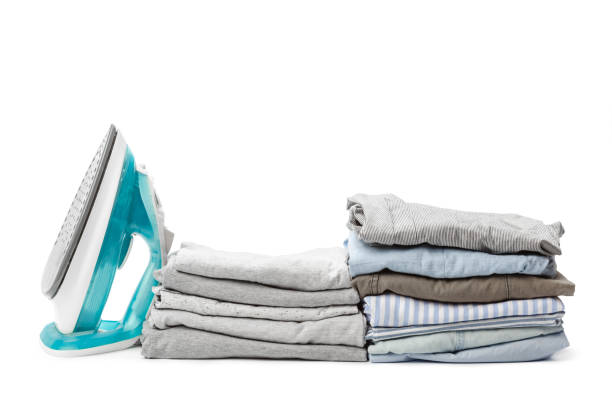 istock Electric iron and pile of clothes. 1154048111