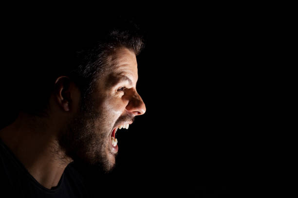istock Angry man shouting out loud isolated on black background. 1154056390