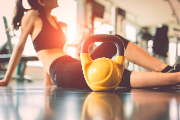 close up kettlebells with woman exercise workout in gym fitness breaking relax after sport training center background. healthy lifestyle bodybuilding and athlete muscle dumbbells. healthcare lifestyle - kettle bell activity aerobics athlete imagens e fotografias de stock