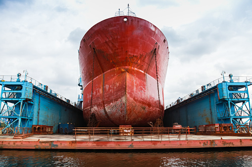Huge red tanker is under repairing in blue dry dock. Front view. Shipyard of Varna, Bulgaria
