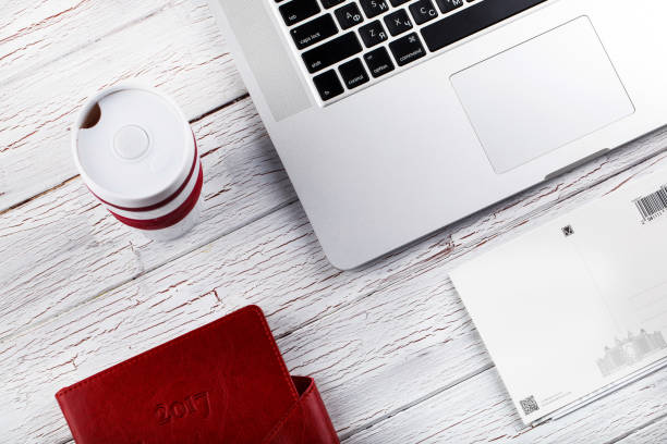 istock Coffee-mug, laptop and diary lie on white table 1154061964
