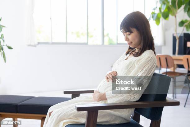 Foto de Barriga De Sucção Da Mulher Gravida No Quarto e mais fotos de stock de Grávida - Grávida, Japonês, Cadeira