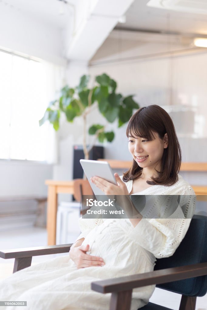 Mulher gravida que usa a tabuleta - Foto de stock de 20 Anos royalty-free