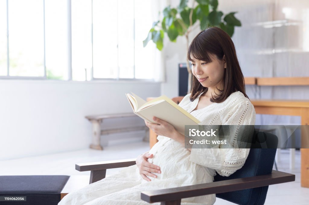 Mulher gravida que lê um livro - Foto de stock de 20 Anos royalty-free