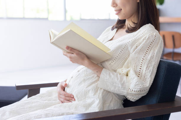 schwangere frau, ein buch zu lesen - window human pregnancy home interior women stock-fotos und bilder