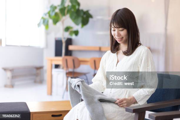 Foto de Mulher Gravida Que Olha A Roupa Das Crianças e mais fotos de stock de Grávida - Grávida, Japonês, Roupa