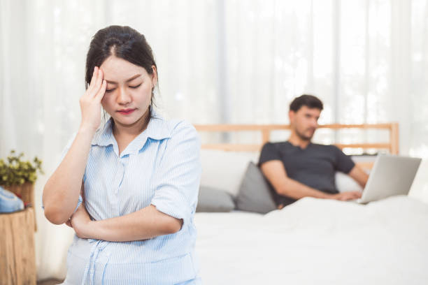 pregnant woman worried about husband neglect to take care of her health and baby. wife with ignored workaholic husband using laptop computer background. social issue problems of family in home bedroom - failure relationship difficulties computer women imagens e fotografias de stock