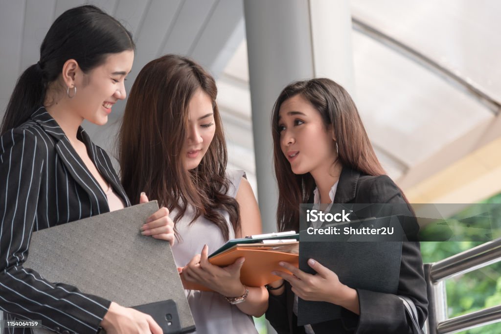 Businesswomen discussing monthly report meeting conference. Group of business people sharing planning working experience at outside office. Secretary having conversation gossip about boss or coworkers Adult Stock Photo