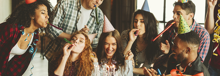 Happy girl with her birthday cake and friends around having fun. Friends birthday party concept