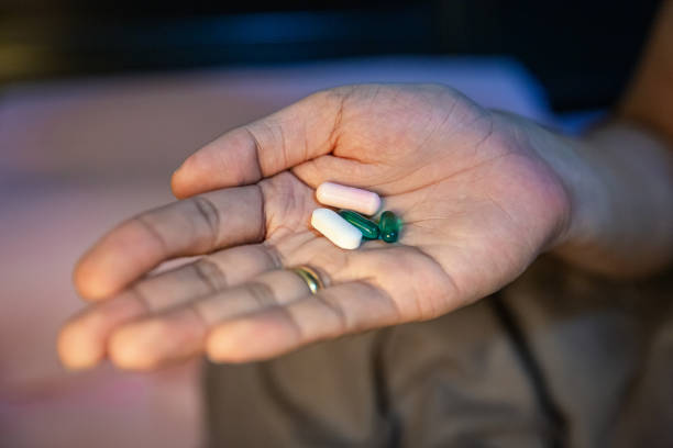 This capsule features a vibrant red half and a pink half, filled with small spherical granules. It may be associated with dietary supplements or medications, showcasing a unique design intended for health applications.