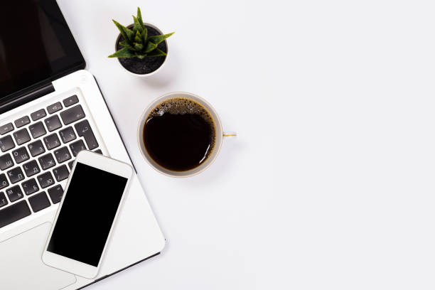 istock Modern workspace with coffee cup, smartphone, paper, notebook, tablet and laptop copy space on white color background. Top view. Flat lay style. 1154071693