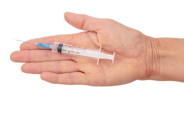 istock Woman's flat hand with plastic disposable, mono use syringe. Isolated on white background. 1154074311