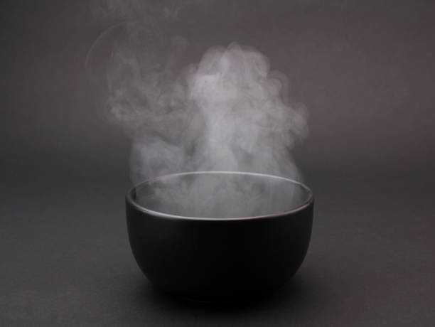 Bowl of hot soup on black background.