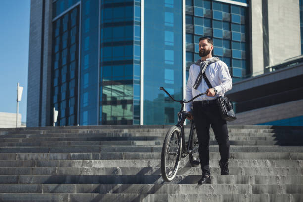 istock Bearded businessman carrying his bicycle on stairs 1154076338