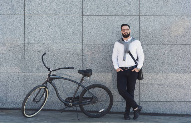 istock Businessman standing against building wall with his bicycle. 1154076372