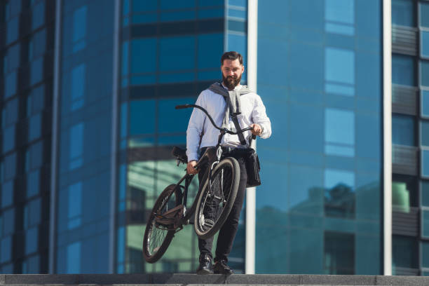 istock Handsome businessman carrying his bicycle while going on stairs 1154076386