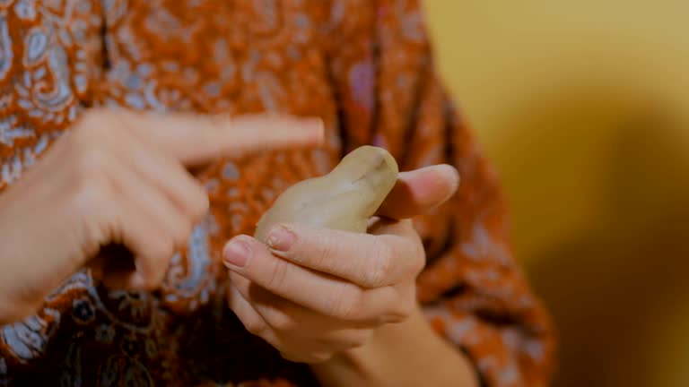 Woman potter making ceramic souvenir penny whistle in pottery workshop