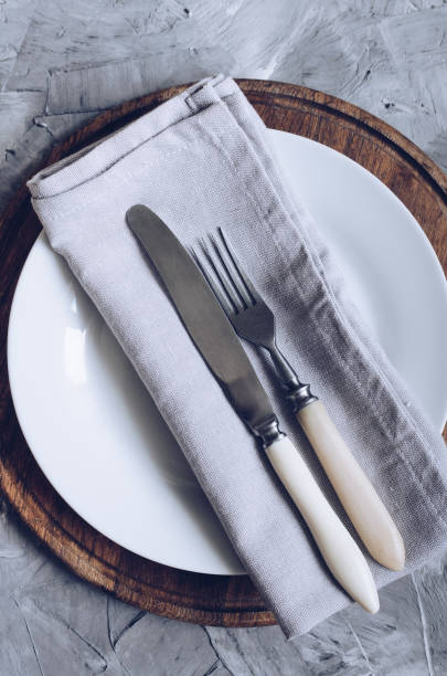 istock Fork, knife and plate on wooden board 1154078040