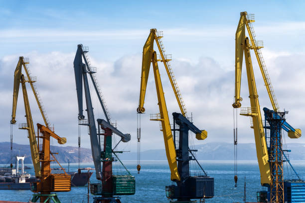 view of old port cranes in seaport on shore of ocean - old crane blue sky imagens e fotografias de stock