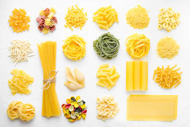 Variety of types and shapes of Italian pasta Variety of types and shapes of Italian pasta in rows on white background from above. Italian cuisine food concept and menu design. Dry pasta background texture. Top view. Flat lay. rigatoni stock pictures, royalty-free photos & images