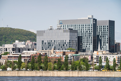 A view of the CHUM hospital center buildings in Montreal, Canada. The Mount Royal is visible on the left, the Saint Lawrence River is in the foreground.