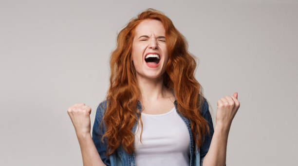 istock Overjoyed young redhead woman screaming with joy 1154080666