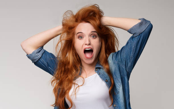 istock Amazed redhead woman clutched her head in surprise 1154080675