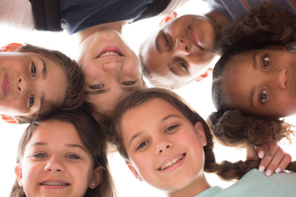 groupe multi-ethnique d’amis d’enfants d’école dans la huddle. - arm around caucasian latin american and hispanic ethnicity child photos et images de collection