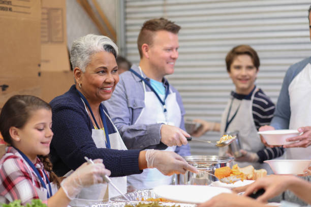 istock Multi-ethnic group of volunteers serves food at soup kitchen. 1154082332