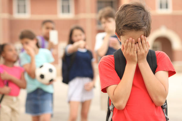ragazzo in età elementare vittima di bullismo a scuola. - bullying child teasing little boys foto e immagini stock