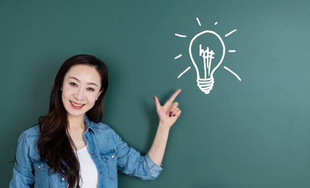 istock Woman pointing light bulb in front of blackboard 1154085470
