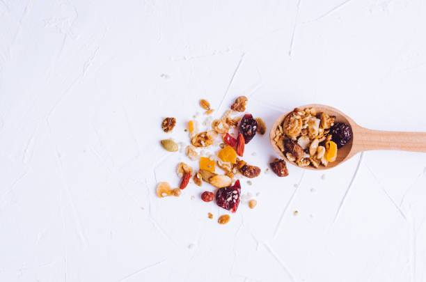 Delicious homemade granola on wooden spoon Delicious homemade granola on wooden spoon on white background. Breakfast. Healthy food sweet dessert snack. Diet nutrition concept. Vegetarian food. Flat lay. Top view. Copy space. dried fruit stock pictures, royalty-free photos & images