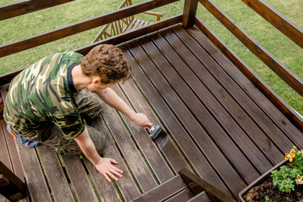 vue de dessus de jeune homme coloration jardin terrasse planches en bois à l’extérieur au printemps. concept de tache de bois de terrasse. - wood stain photos et images de collection