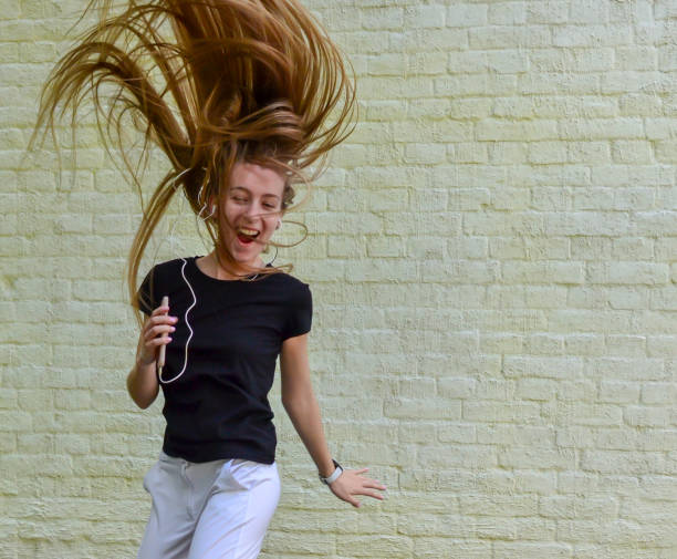 istock Happy young woman in earphones dancing and smiling 1154086607