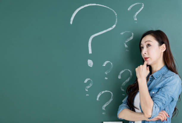 istock Woman in front of blackboard with question marks 1154086790