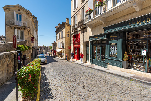 Saint Emilion, France - May 31 2019: well known for its Bordeaux wines, Saint Emilion is also a picturesque medieval village, very popular with its cobbled streets, old houses, ramparts, its castle and its numerous wine merchants, like here is the main street downtown.