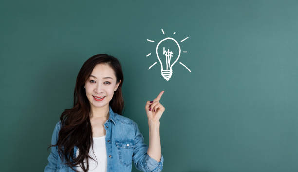 istock Woman pointing light bulb in front of blackboard 1154087363